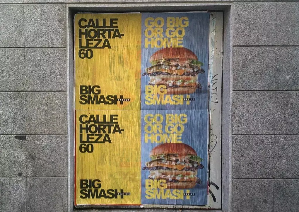 cuatro carteles pegados en el hueco de una pared en Madrid para hamburguesería